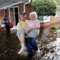 Bob Richling carries Iris Darden, 84, out of her flooded home in the aftermath of Hurricane Florence in Spring Lake, N.C., on Sept. 17. The day is fast approaching when fires, droughts and storms exacerbated by global warming will dwarf our ability to respond. | AP