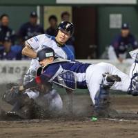 Fighters shortstop Takuya Nakashima slides home to beat Lions catcher Tomoya Mori on Wednesday night at Asahikawa Starffin Stadium. Hokkaido Nippon Ham won 4-0. | KYODO