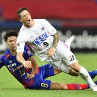 Sagan Tosu striker Fernando Torres is tackled from behind by FC Tokyo midfielder Kento Hashimoto on Sunday night at Ajinomoto Stadium. | KYODO
