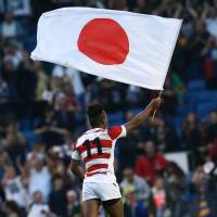 Japan\'s Kotaro Matsushima waves a Japanese flag following the Brave Blossom\'s shocking win over South Africa during the 2015 Rugby World Cup on Sept. 19, 2015, in Brighton, England. | AFP-JIJI