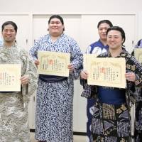 New wrestlers display their certificates of completion after graduating from the sumo school\'s orientation class, which is administered regularly at Ryogoku Kokugikan. | KYODO