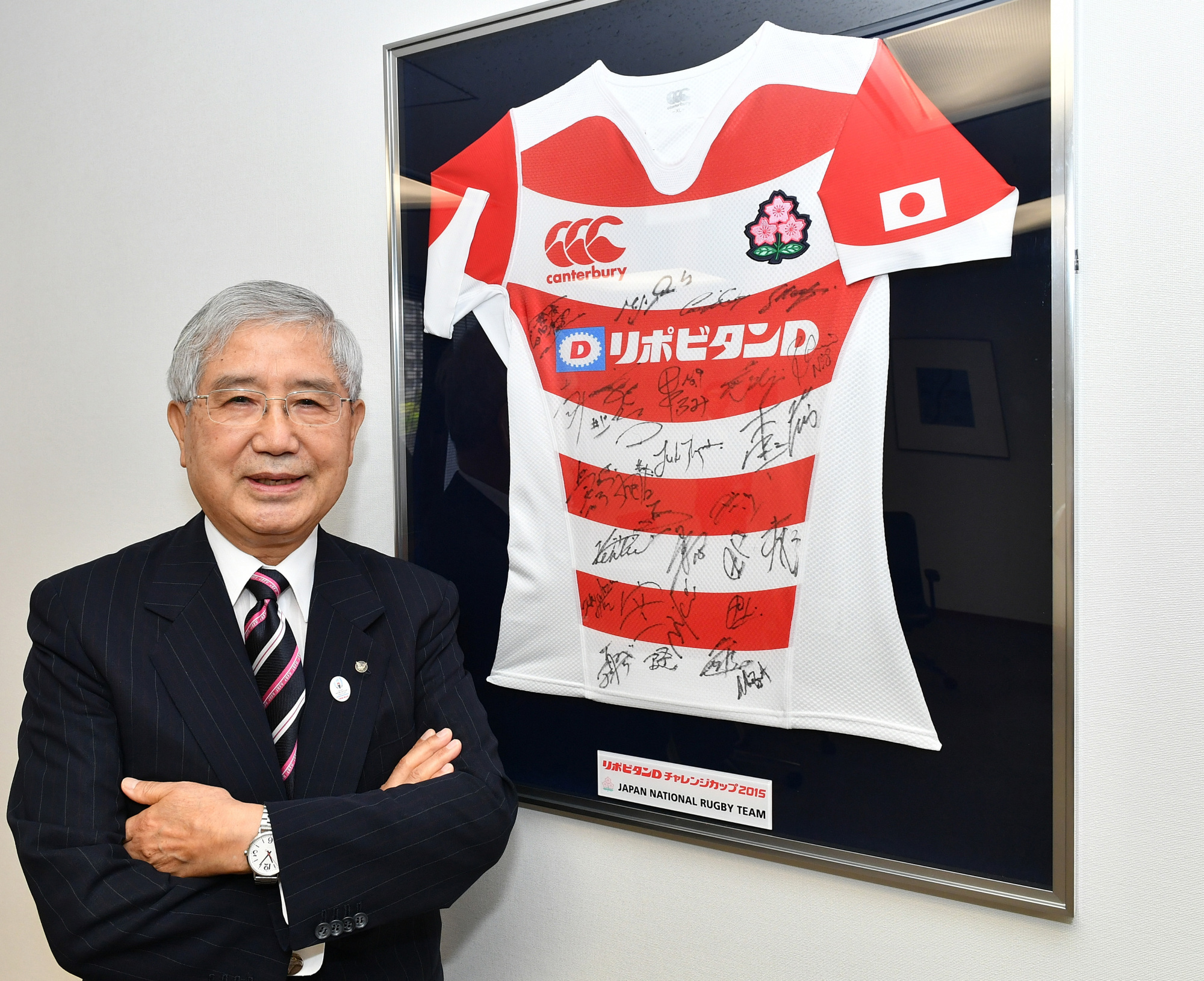 Akira Uehara poses before the autographed Japan rugby team's jersey earlier this month in his office at Taisho Pharmaceutical Co., Ltd. in Toshima Ward, Tokyo. | YOSHIAKI MIURA