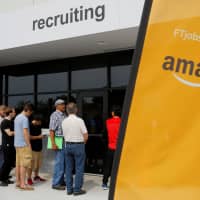 Job seekers line up to apply during \"Amazon Jobs Day,\" a job fair at the Amazon.com Fulfillment Center in Fall River, Massachusetts, in 2017. | REUTERS