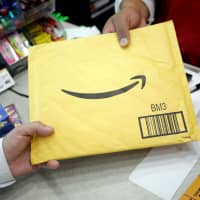 A customer picks up an Amazon package at a Femsa\'s Oxxo convenience store in Monterrey, Mexico, in August. | REUTERS