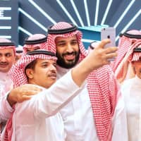 A handout picture provided by the Saudi Royal Palace on Tuesday shows Saudi Crown Prince Mohammed bin Salman (center) posing for a selfie with an unidentified man near Saudi billionaire Prince Al-Walid bin Talal (right) during the Future Investment Initiative FII conference in Riyadh. Saudi Arabia is hosting the key investment summit overshadowed by the killing of critic Jamal Khashoggi that has prompted a wave of policymakers and corporate giants to withdraw. | BANDAR AL-JALOUD / SAUDI ROYAL PALACE / VIA AFP-JIJI