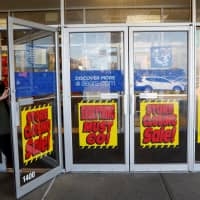 A woman walks out the door past signs advertising store closing at a Sears istore n New Hyde Park, New York, Wednesday. | REUTERS