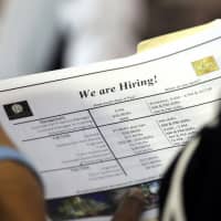 A job applicant looks at job listings for the Riverside Hotel at a job fair hosted by Job News South Florida, in Sunrise, Florida, in June. | AP