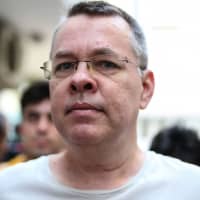 U.S. pastor Andrew Brunson is escorted by Turkish plain clothes police officers in July. | AFP-JIJI