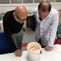 Lancaster University researchers Mohamed Saafi and Hasan Hasan look into a bucket containing carrot mixture to be added to concrete in their laboratory in Lancaster, England, on Oct. 2. | REUTERS