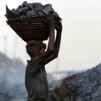 An coal scavenger carries a basket of coal collected at a mine in the district of Dhanbad, in India\'s Jharkhand state, at the end of June last year. | AFP-JIJI