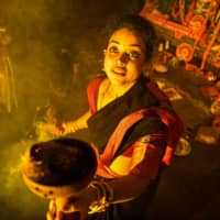 An Indian Bengali Hindu devotee performs a Dhunuchi Nach dance in front of an idol of the goddess Durga during an Arti ritual in New Delhi on Thursday, a day before the festival of Dussehra ends the Navratri Festival, symbolizing the triumph of good over evil. At its culmination, firecracker-stuffed effigies of the demon king are set alight. | AFP-JIJI