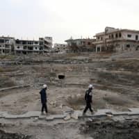 Members of the Civil Defense, also known as the \"White Helmets,\" are seen inspecting the damage at a Roman ruin site in Daraa, Syria, last December. | REUTERS