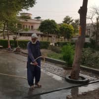 A gardener washes a walkway in Lahore\'s Johar Town area on Tuesday. A petition being heard before the Lahore High Court seeks to stop the city from using 30,500 liters of water each day to wash its streets. | THOMSON REUTERS FOUNDATION / WAQAR MUSTAFA