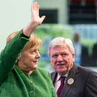 German Chancellor Angela Merkel waves as she and Volker Bouffier, Hesse state premier and deputy chairman of the Christian Democratic Union, arrive at an election rally in Fulda, western Germany, on Thursday. | AFP-JIJI