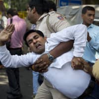 A policeman takes away a Congress party worker during a protest against Junior External Affairs Minister M.J. Akbar in New Delhi on Monday. | AP