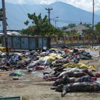 Tsunami survivor Ahmad Ibrahim (right) looks for his wife, Fahria, among bodies lined up outside Undata hospital in Palu in Central Sulawesi on Tuesday, four days after a strong earthquake and tsunami hit the area. The Indonesian government said the death toll from a devastating quake-tsunami on the island of Sulawesi had risen to 1,234 people, up from the previous count of 844. | AFP-JIJI