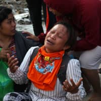 A woman grieves as she waits for an Indonesian rescue team searching for survivors at a collapsed building in Palu, Indonesia\'s Central Sulawesi, on Tuesday. | AFP-JIJI