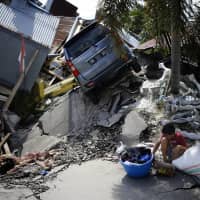 A boy sits with items salvaged from the ruins of a family member\'s house in the Balaroa neighborhood in Palu, Central Sulawesi, Indonesia, Tuesday. | AP