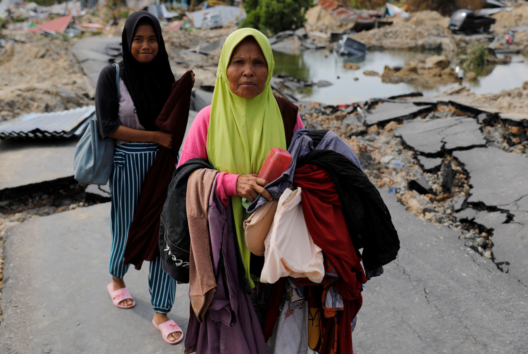 Women carry clothes from the ruins of their house in Palu on Thursday. | REUTERS