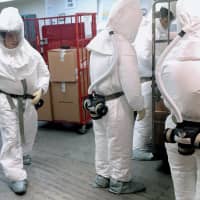 U.. Defense Department personnel, wearing protective suits, screen mail as it arrives at the Pentagon in Washington Tuesday. Two or more packages delivered to the Pentagon this week were suspected to contain the deadly poison ricin, an official said. | AFP-JIJI