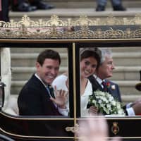Britain\'s Princess Eugenie of York and her husband Jack Brooksbank get into the Scottish State Coach at the start of their carriage procession following their wedding at St. George\'s Chapel, Windsor Castle, in Windsor on Friday. | AFP-JIJI