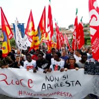 Migrants demonstrate in support of Mayor Domenico Lucano in front of his house in the southern Italian town of Riace, Oct. 6. The banner reads: \"You can\'t arrest Riace.\" | REUTERS
