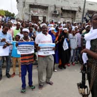 A security officer stands guard as civilians gather near the scene to mark the first anniversary of a terror attack in the Hodan district of Mogadishu Sunday. | REUTERS