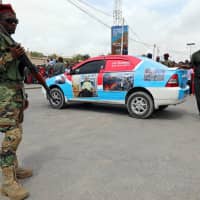 Security officers stand guard as civilians gather near the scene to mark the first anniversary of a terror attack, in the Hodan district of Mogadishu Sunday. | REUTERS