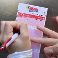 A woman fills out a Mega Millions lottery ticket on Friday in New York City. | AFP-JIJI