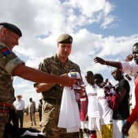 The Duke of Cambridge, Prince William (center), gives sports uniforms to members of a community soccer team during his visit to the Ol Maiso primary school in Laikipia on Sunday. | AFP-JIJI