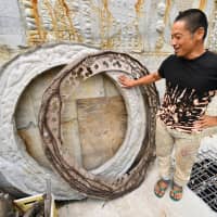 Oka shows off a doughnut-shaped concrete object he made after being inspired by giant stone coins used on the Micronesian island of Yap. | YOSHIAKI MIURA