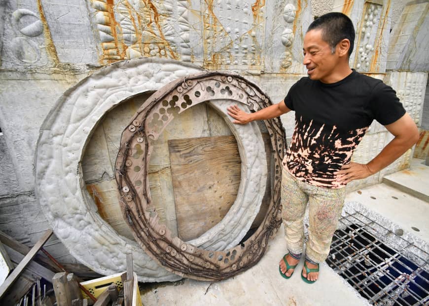 Oka shows off a doughnut-shaped concrete object he made after being inspired by giant stone coins used on the Micronesian island of Yap.