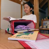 Fuku Kutsuwa, a fourth grader at Gifu Elementary School in the city of Gifu, shows off her school backpack, which has become much lighter to carry around, after the school recently allowed its students to keep their textbooks and other study materials at school. | CHUNICHI SHIMBUN
