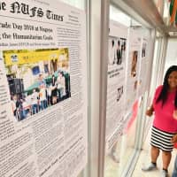 Cassandra Evangelista (right) looks at enlarged pages of an English-language newspaper on display at Nagoya University of Foreign Studies in Nisshin, Aichi Prefecture. | CHUNICHI SHIMBUN