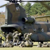 Ground Self-Defense Force and British Army personnel disembark a helicopter during a joint drill at the GSDF\'s training school in Shizuoka Prefecture on Tuesday. | KYODO