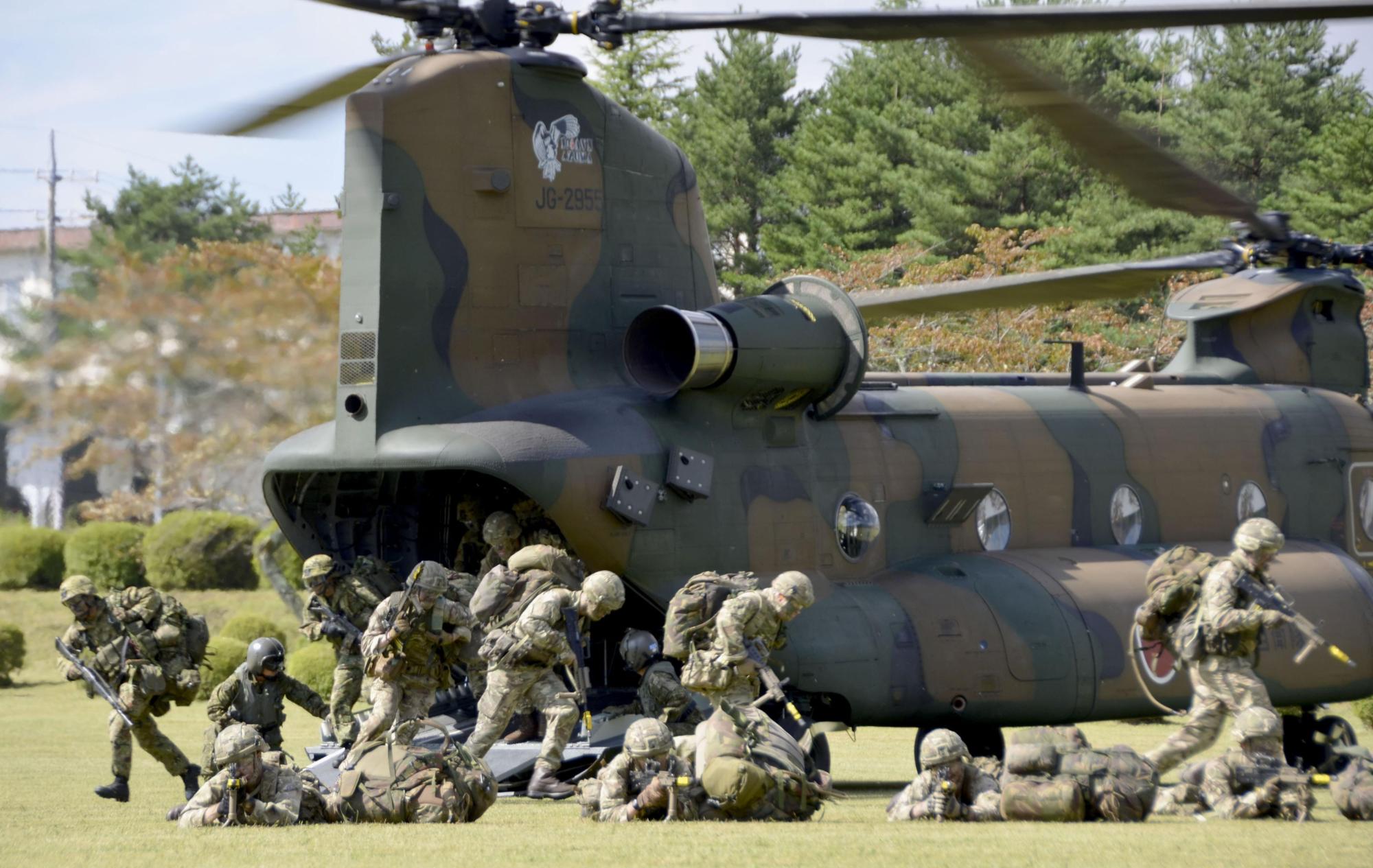 Ground Self-Defense Force and British Army personnel disembark a helicopter during a joint drill at the GSDF's training school in Shizuoka Prefecture on Tuesday. | KYODO