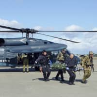 A U.S. military pilot on a stretcher is carried out from an Air Self-Defense Force helicopter at Misawa Air Base, in Aomori Prefecture, as part of a joint Japanese and U.S. rescue drill the same day. | KYODO