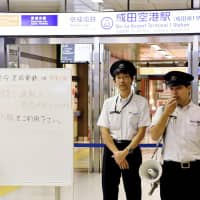 Keisei Electric Railway Co. employees ask stranded passengers to transfer to the JR line Friday morning at Narita Airport Terminal 1 Station after Keisei was hit by power outages likely caused by seawater residue carried by Typhoon Trami. | KYODO