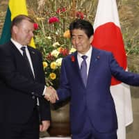 Prime Minister Shinzo Abe greets his Lithuanian counterpart Saulius Skvernelis before their talks in Tokyo on Friday. | KYODO