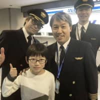 The world\'s youngest Othello game champion, Keisuke Fukuchi (front left), and All Nippon Airways Capt. Kunihiko Tanida (front right) pose for photos at Narita airport on Monday. | ALL NIPPON AIRWAYS CO. / VIA KYODO