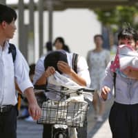 High school students endure scorching heat in Tajimi, Gifu Prefecture, in August. The ruling Liberal Democratic Party has given up the idea of introducing daylight saving time during the 2020 Tokyo Olympic and Paralympic Games, citing technical difficulties. | KYODO