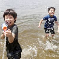 Children play with water on the beach in the Odaiba district in Tokyo\'s Minato Ward on June 9. A plan to filter bacteria from the water around the beach was announced Friday by the 2020 Olympic organizers. | KYODO