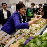 Tokyo Gov. Yuriko Koike inspects wasabi at the new Toyosu fish market Thursday. | REUTERS
