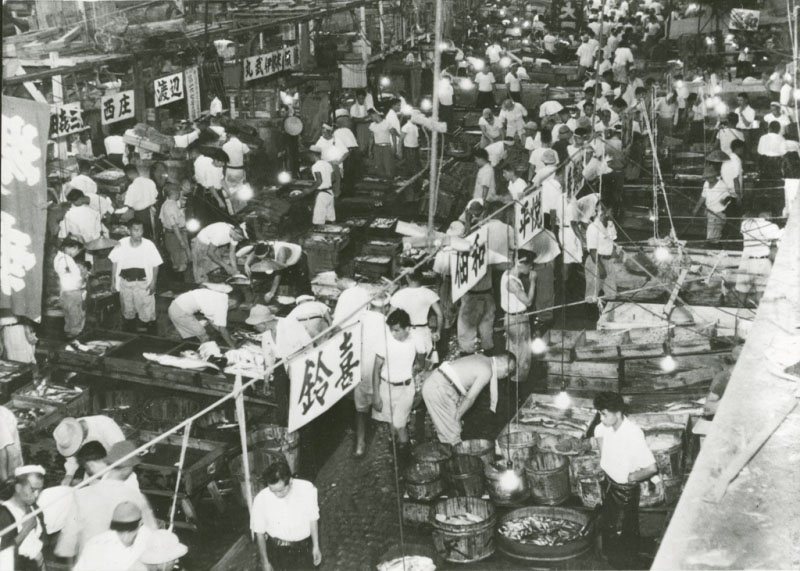 Buyers and sellers complete transactions at the Tsukiji fish market in this photo taken sometime between 1955 and 1964. | TOKYO METROPOLITAN GOVERNMENT