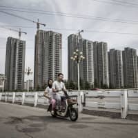 A Chinese couple ride an electric scooter in Shandong province. Asia\'s emerging middle class appears open to the idea of e-scooters if the price is right and charging is convenient. | BLOOMBERG