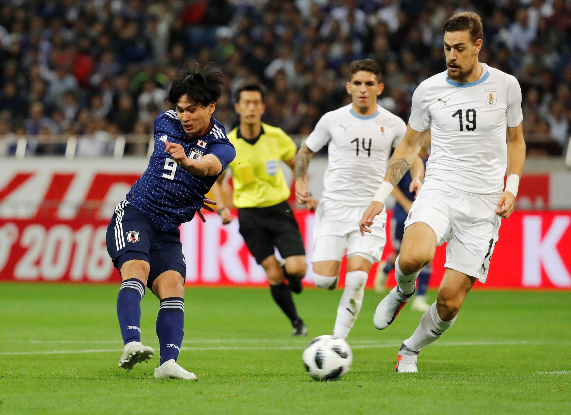Takumi Minamino scores the opening goal for Japan against Uruguay on Tuesday in Saitama. | REUTERS