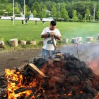 Stones are heated in a fire to lay a hangi, a traditional Kiwi meal, at the Jozankei club grounds in Sapporo in July. | HOKKAIDO BARBARIANS / VIA KYODO