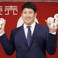 Giants ace Tomoyuki Sugano poses at a news conference holding baseballs celebrating his second straight Sawamura Award on Monday. | PRESIDENTIAL PRESS SERVICE / POOL / VIA AP