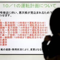 A woman is silhouetted against a screen showing trains that were halted due to Typhoon Trami at JR Sapporo Station in the city on Monday morning.  | KYODO