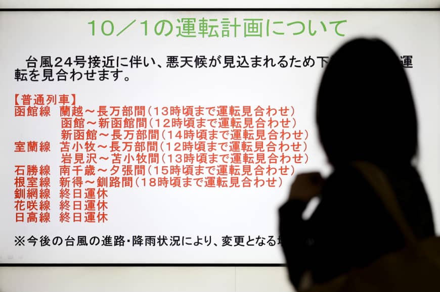 A woman is silhouetted against a screen showing trains that were halted due to Typhoon Trami at JR Sapporo Station in the city on Monday morning. 